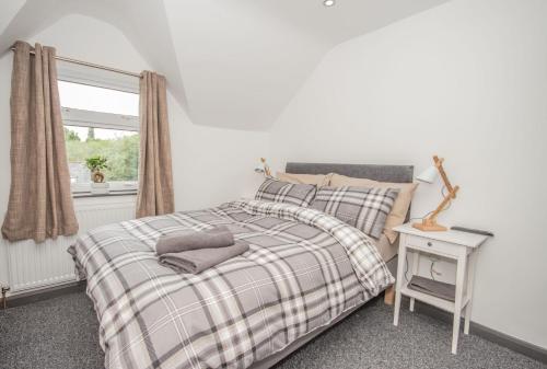 考文垂Featherbed Cottage的一间卧室配有一张带铺着地毯的床和窗户。
