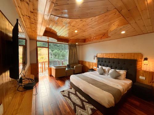 马拉里Himalayan Riverside Resort, Manali的一间卧室设有一张带木制天花板的大床