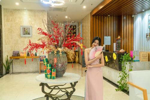 岘港Star City Riverside Hotel By Haviland的站在大厅的身着粉红色衣服的女人