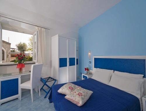 伊斯基亚伊姆帕拉马尔酒店的蓝色和白色的卧室配有一张床和一张书桌