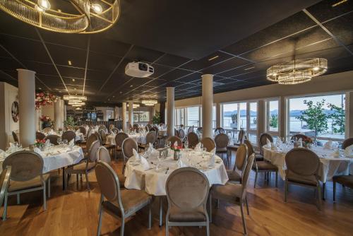莫尔德Molde Fjordhotell - by Classic Norway Hotels的宴会厅配有白色的桌椅和窗户