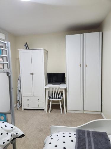 IfieldRoom in Crawley/Gatwick/West Sussex的卧室配有白色橱柜和书桌。