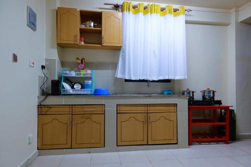 ThikaGazena homes的厨房配有木制橱柜和白色窗帘