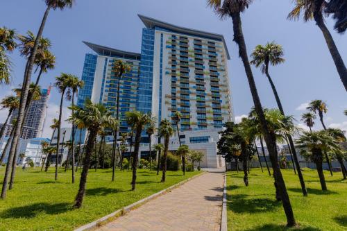巴统Bellevue Residential Hotel Batumi的一条棕榈树的走道,在一座高大的建筑前