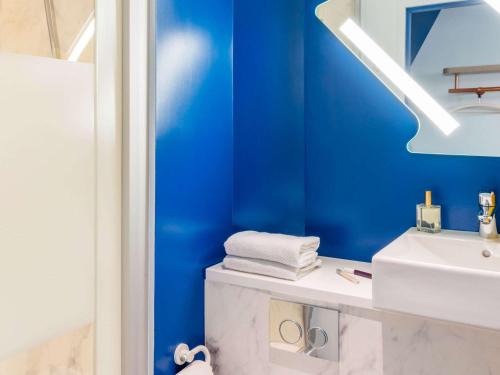 亚眠亚眠中心宜必思快捷火车站酒店的浴室设有蓝色的墙壁和白色的盥洗盆。