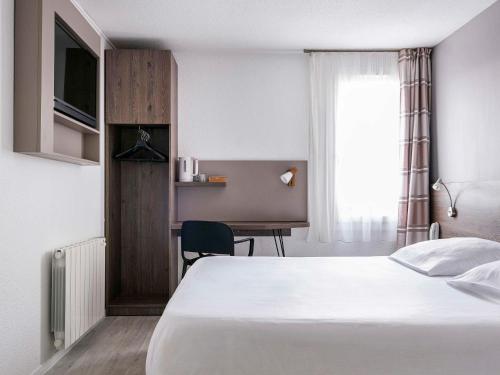 马西约HOTEL Lyon Nord Massieux Genay的配有一张床和一张书桌的酒店客房
