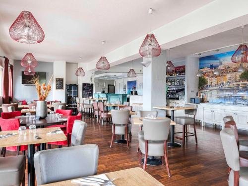 马西约HOTEL Lyon Nord Massieux Genay的一间带桌椅的餐厅和一间酒吧