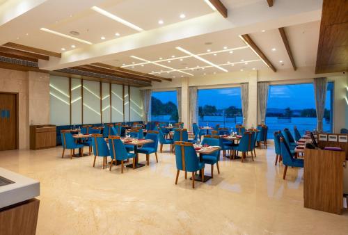 贾姆讷格尔The Orchid Jamnagar的餐厅设有蓝色的椅子和桌子以及窗户。