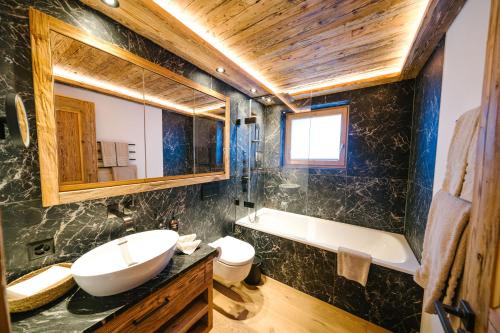 克洛斯特斯瑟纽斯Seven Alpina Boutique Hotel的一间带水槽、浴缸和卫生间的浴室