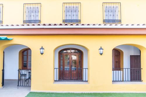 格拉纳达Casa Rural "compartida" La Loma的黄色的房子,设有两扇门和阳台