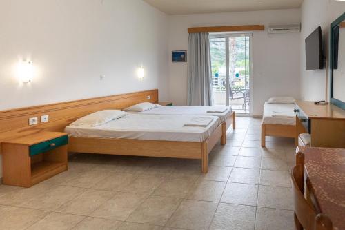 罗德岛卡利地亚Faliraki Dream Hotel的一间卧室配有两张床、一张桌子和一台电视。
