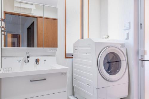 东京Residencial Voyan 南砂町的白色的浴室设有洗衣机和水槽。