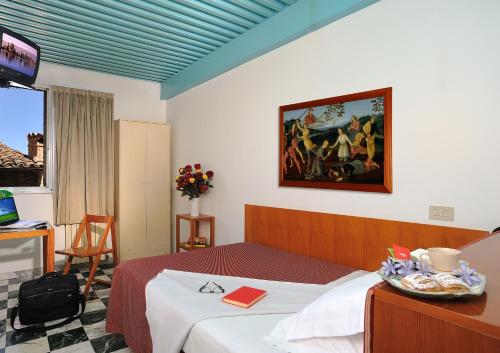 乌尔比诺Hotel Raffaello - Self Check-in Free的酒店客房设有一张床,墙上挂有绘画作品