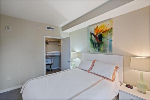 圣何塞Global Luxury Suites San Jose Downtown的卧室配有白色的床和墙上的绘画作品
