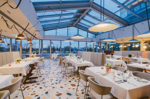 巴特塔茨曼斯多夫Hotel Reiters Finest Family的餐厅设有白色的桌椅和窗户。