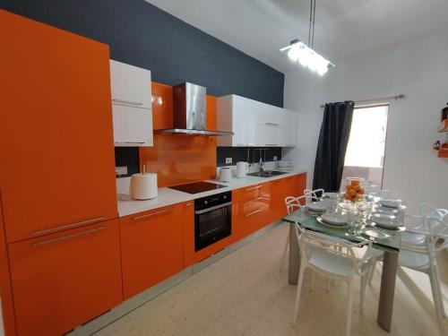 瓦莱塔Tal-Munfuha- Centrally Located Space.的厨房配有橙色橱柜和桌椅