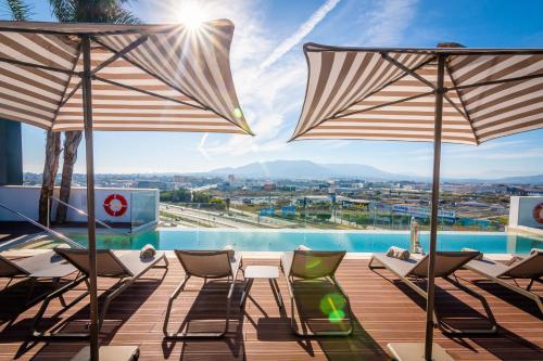 马拉加Hotel Málaga Vibes的一个带椅子和遮阳伞的甲板和一个游泳池