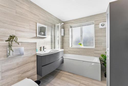 诺丁汉Stylish Nottingham House - Parking - Garden的浴室设有白色浴缸、水槽和浴缸。