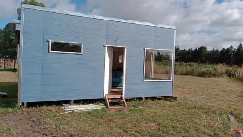 弗鲁蒂亚尔Cabaña familiar的坐在田野里的蓝色小房子