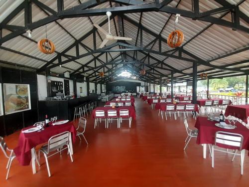 图马科Hotel & Resort Villa del Sol的宴会厅配有红色桌子和白色椅子