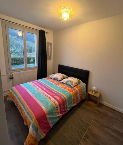 VoiteurGITE LE MAGNOLIA的一间卧室配有一张带彩色毯子和窗户的床。