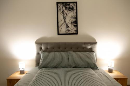 斯科普里Horizon Grey Apartment & Spa的一间卧室配有一张带两盏灯和一张照片的床。