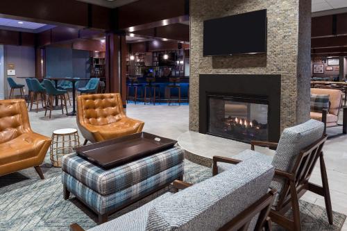 麦迪逊福朋亨茨维尔机场酒店的一个带壁炉和椅子的大堂以及一间酒吧