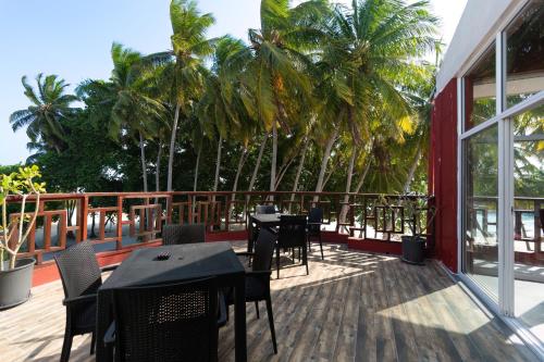 呼拉Silver Oasis Maldives的棕榈树甲板上配有桌椅的天井