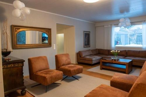 塞伊奈约基Villa Närhi 230 m2 upea talo rauhallisella alueella的客厅配有沙发、椅子和桌子