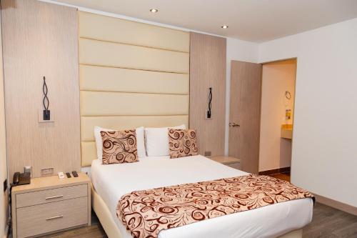 麦德林Hotel Laureles Loft的一间卧室配有一张大床和一个床头柜