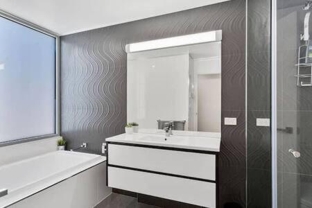霍巴特New Architect designed Coastal retreat-water views的一间带水槽、浴缸和镜子的浴室