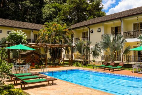 佩尼多里约佩妮多酒店的房屋旁的游泳池配有椅子和遮阳伞