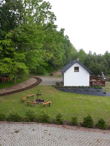 ParchowoLeśny Zakątek- Domek Lipa的一个带白色建筑和野餐桌的院子