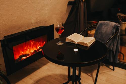 IeriķiRose Valley Cottage的一杯葡萄酒和壁炉旁的桌子上的一本书