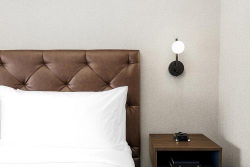 基洛纳基洛纳机场福朋喜来登酒店的一张带白色枕头和边桌的床