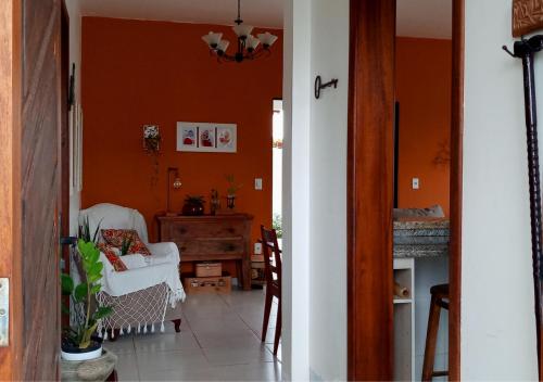佩尼亚Casa de Praia Penha, Beto Carrero, 500m da Praia da Armação的客厅设有橙色墙壁和白色椅子