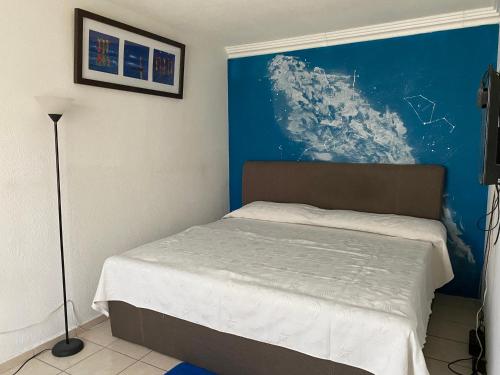 El JacalSammus House的一间卧室配有一张蓝色墙壁的床