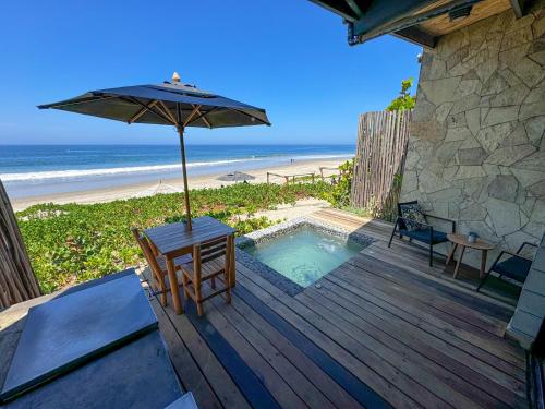 维加伊托DIEM Vichayito Beachfront Eco-Luxury的木制甲板配有遮阳伞和桌椅