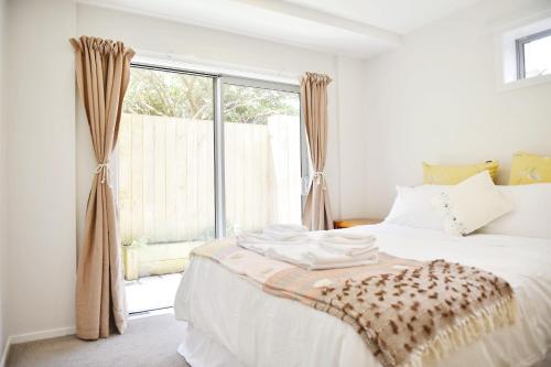 惠灵顿Johnsonville Brand New Lovely townhouse的卧室配有白色的床和窗户