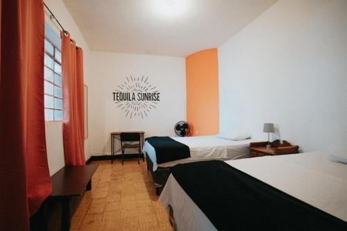危地马拉Tequila Sunrise Hostel的酒店客房设有两张床,墙上有标志