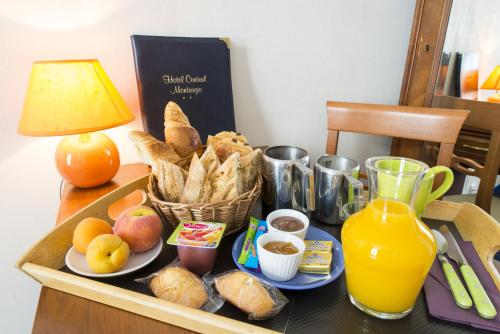 蒙塔日Logis Hôtel Central的桌上的食品托盘,包括面包和橙汁
