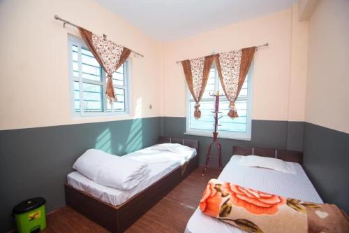 TānsenRanimahal Homestay的一间卧室设有两张床和两个窗户。