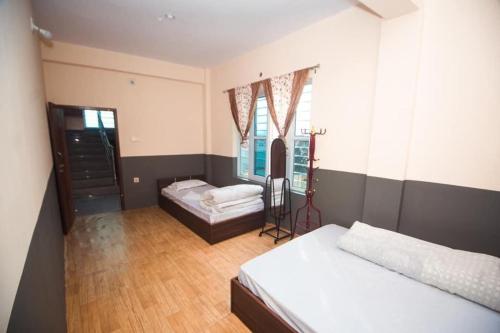 TānsenRanimahal Homestay的一间卧室设有两张床和窗户。