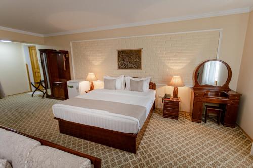 撒马尔罕Hotel Grand Samarkand Superior - B的配有一张大床和镜子的酒店客房