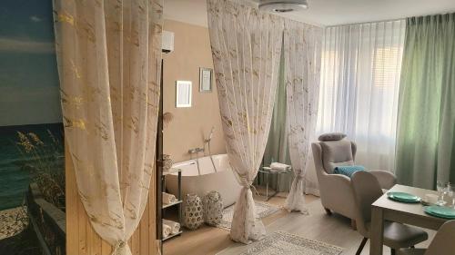 弗瓦迪斯瓦沃沃Elegante-Kameralny Aparthotel的客厅配有窗帘、椅子和桌子