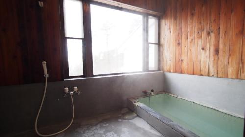 草津Private hot-spring Villa in Kusatsu的带浴缸和窗户的浴室