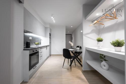 塞萨洛尼基WeStay Apartments, The Luxury Suites的厨房配有白色的柜台和桌椅