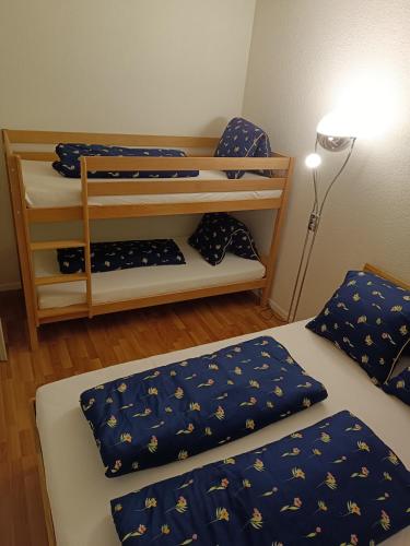 因特拉肯Apartment Jolie的一间设有两张带蓝色床单和灯的床的房间