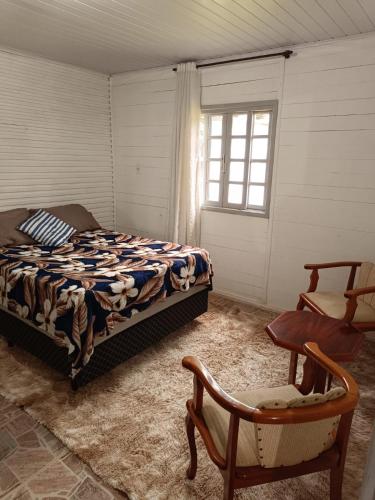 拉热斯Casa Amarela的卧室配有床、椅子和窗户。
