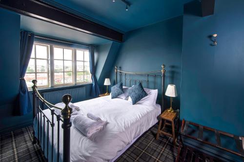 斯卡伯勒The Victoria Hotel的一间卧室配有一张蓝色墙壁的床和一扇窗户